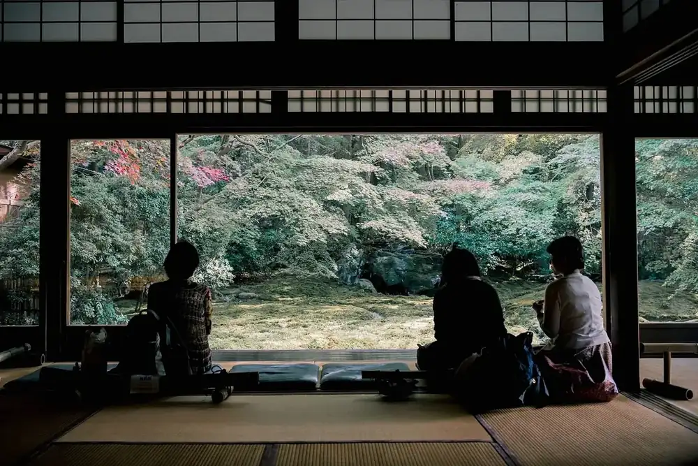 Seated people looking out over a garden from a traditional Japanese hall